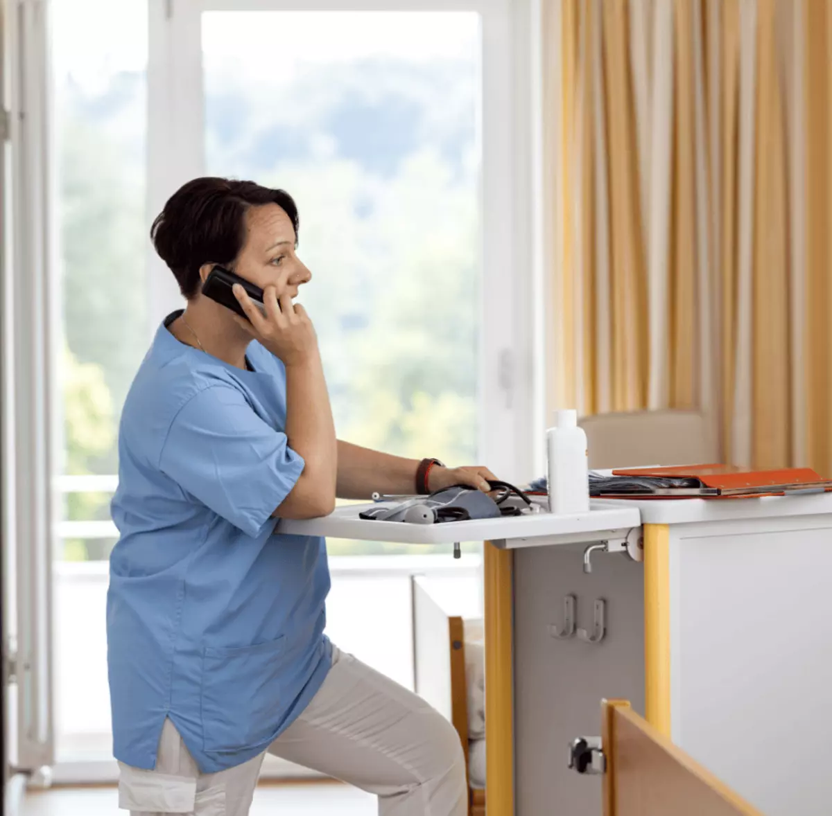 Frau steht am Empfangstresen und telefoniert – freundlicher Service für Ihre Reha-Anfragen.