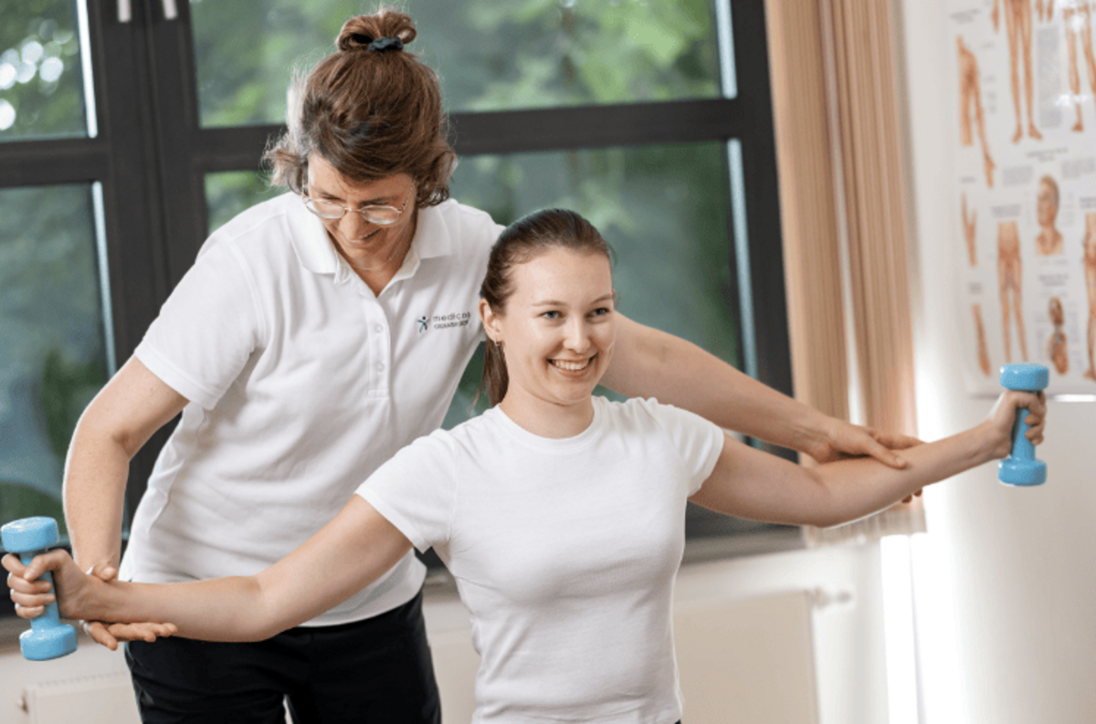 Therapeutin macht Übungen mit Patientin auf Gymnastikball – ärztlich verordnete Sporttherapie zur körperlichen und psychischen Rehabilitation.