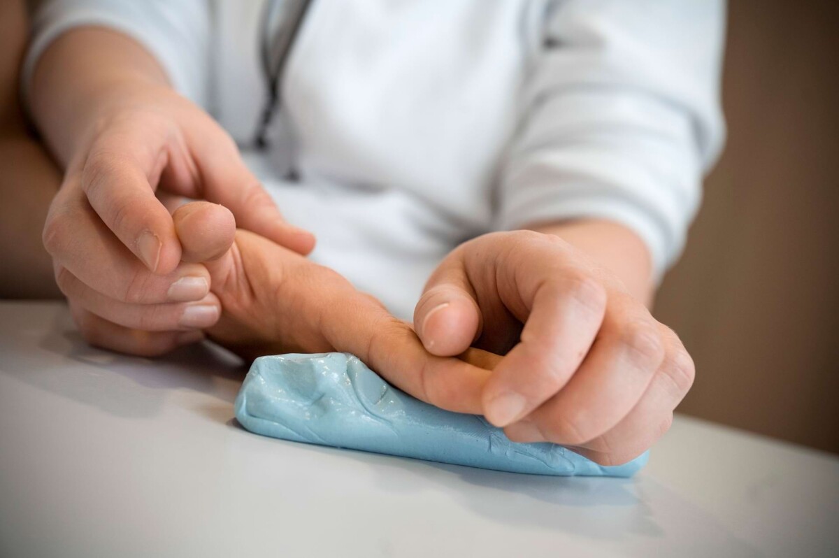 Behandler untersucht die Hand einer Patientin – neurologische Rehabilitation zur Wiederherstellung motorischer Funktionen.