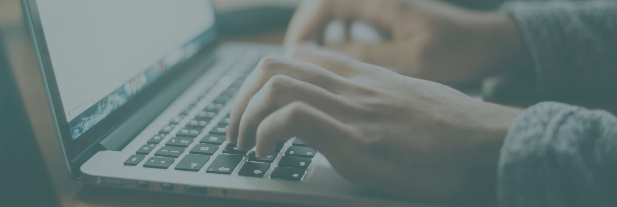 Detailaufnahme von Fingern, die auf einer Notebook-Tastatur tippen