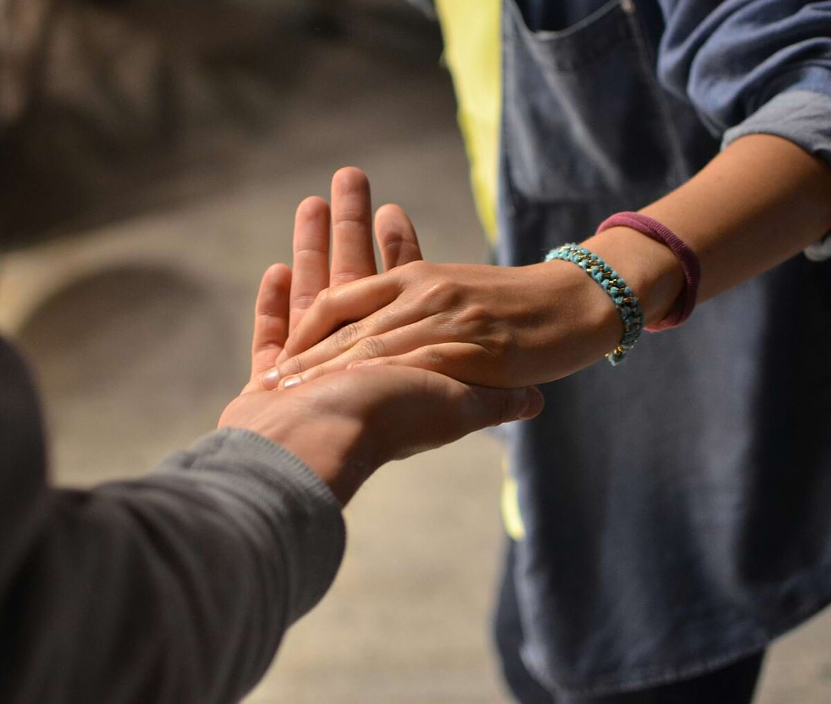 Zwei Personen halten sich fürsorglich und unterstützend die Hand