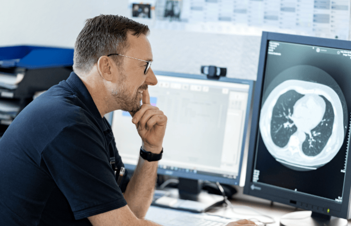 Person sitzt am Computer und betrachtet ein medizinisches Untersuchungsbild – digitale Nachsorge zur langfristigen Gesundheitsförderung.