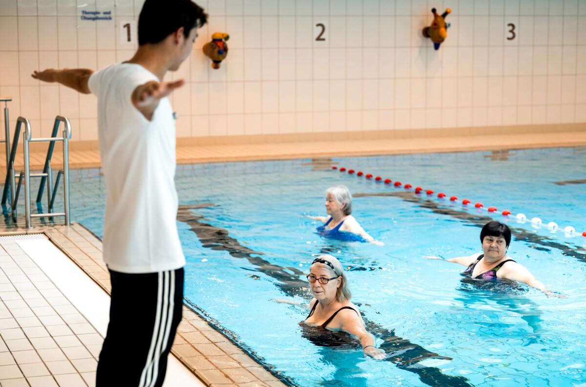 Trainer führt eine Gruppe bei einer Wassertherapie an – Teil der umfassenden Therapieangebote in der Reha-Klinik.